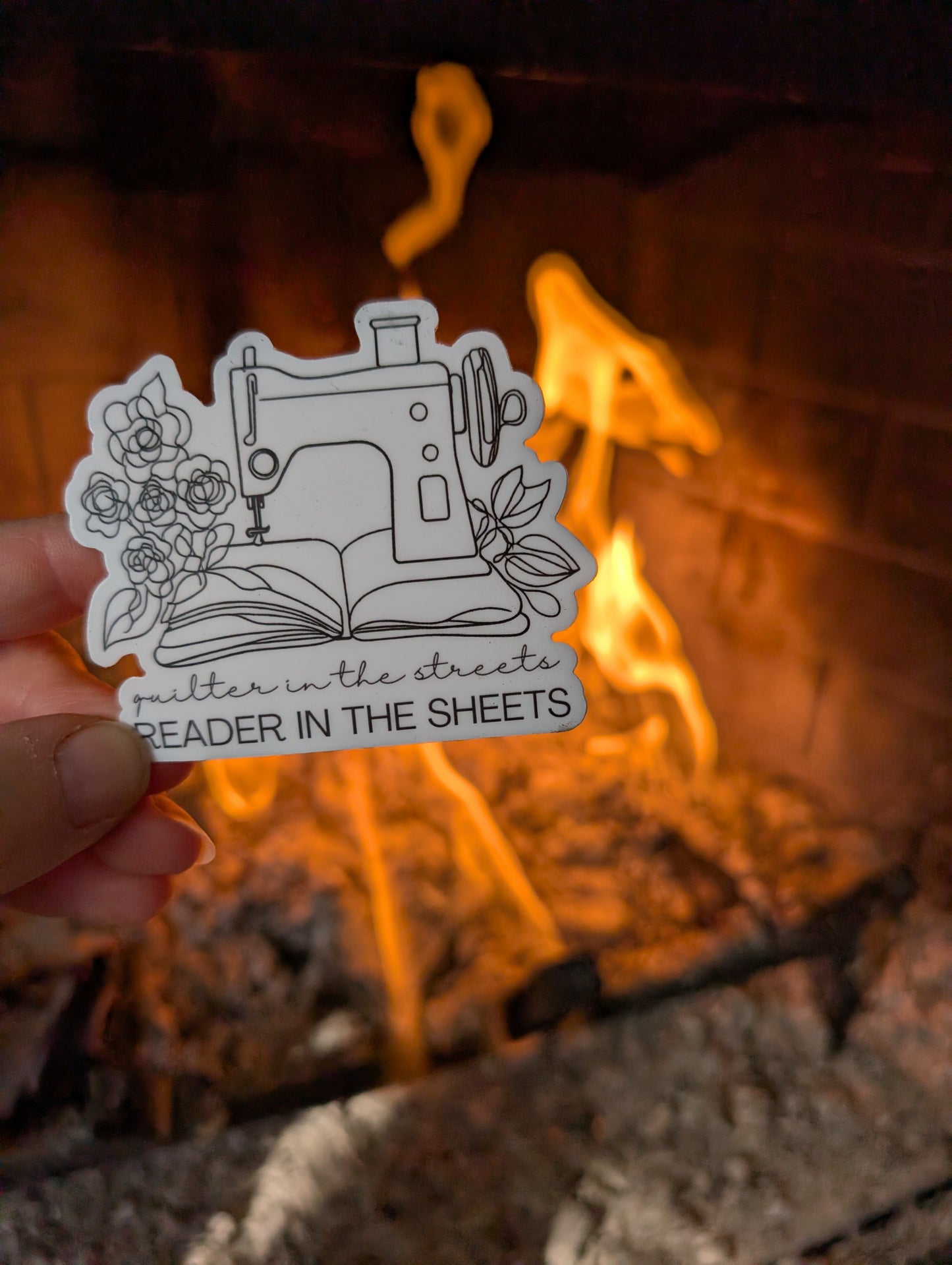 Sticker with sewing machine design held in front of a fireplace